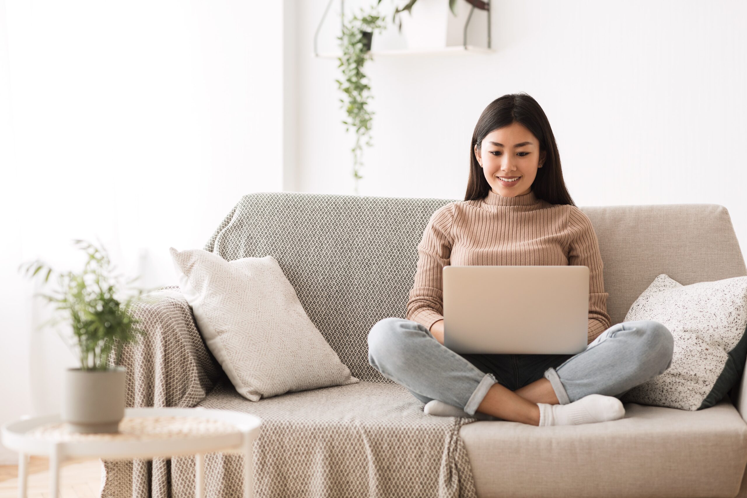 Woman on Couch Looking at Laptop