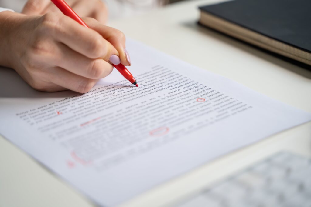 Woman copyediting a paper with a red pen.